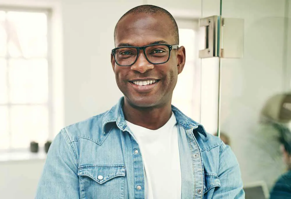 happy black man with glasses and a jean shirt smiling