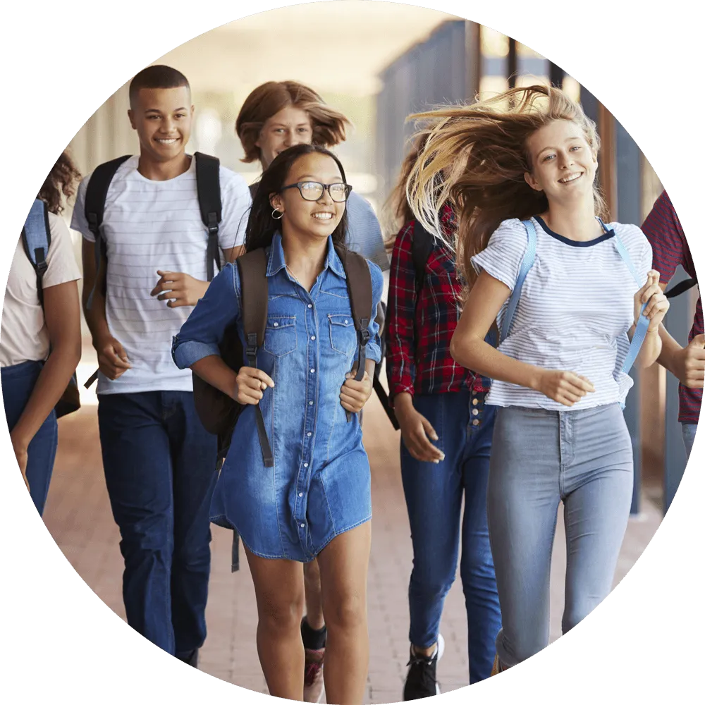 Group of teens walking down the hallways at school smiling