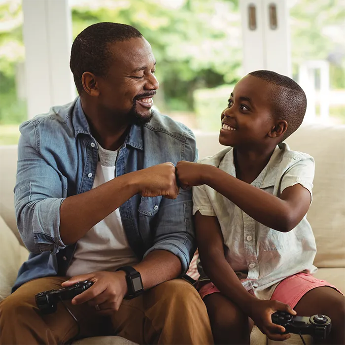 father and son playing video games together and smiling